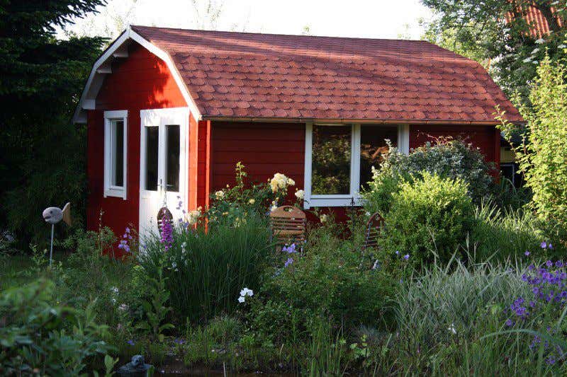 Ein echter Hingucker: Dieses Gerätehaus in Schwedenrot bildet einen schönen Kontrast zu den blauen Blumen.