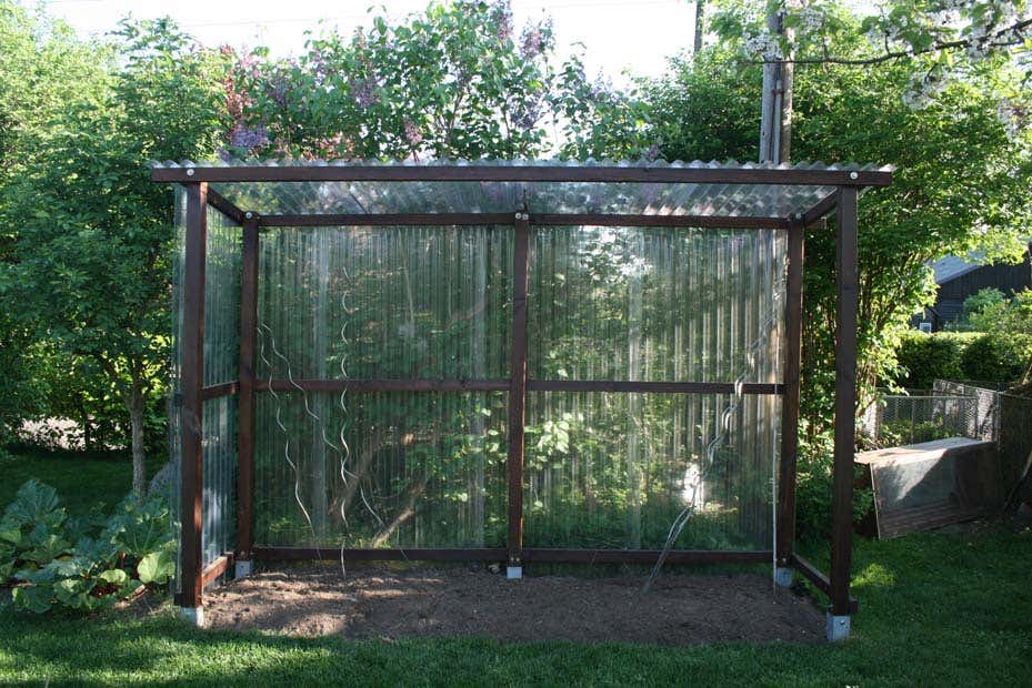 Das unbepflanzte Tomatenhaus, kontruiert aus Holzbalken und Wellplatten.