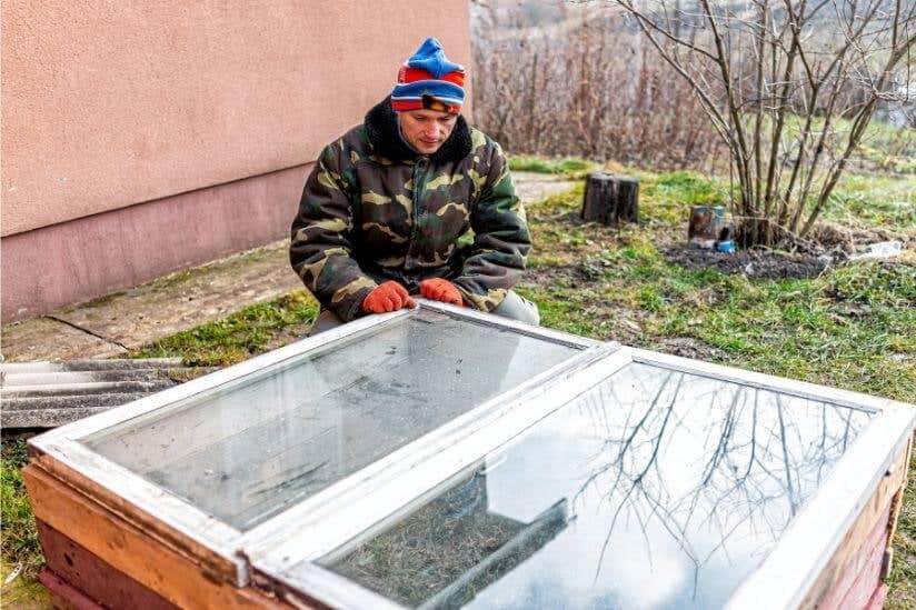 Mann sitzt vor alten Fenstern